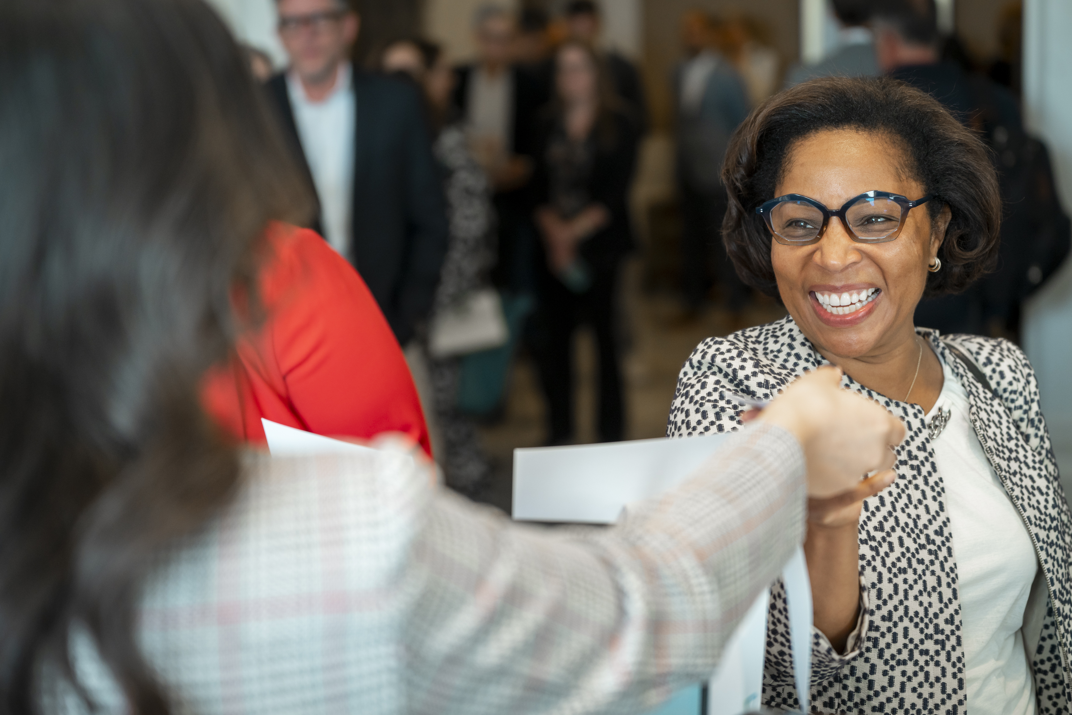A smiling lady collects a badge at the event