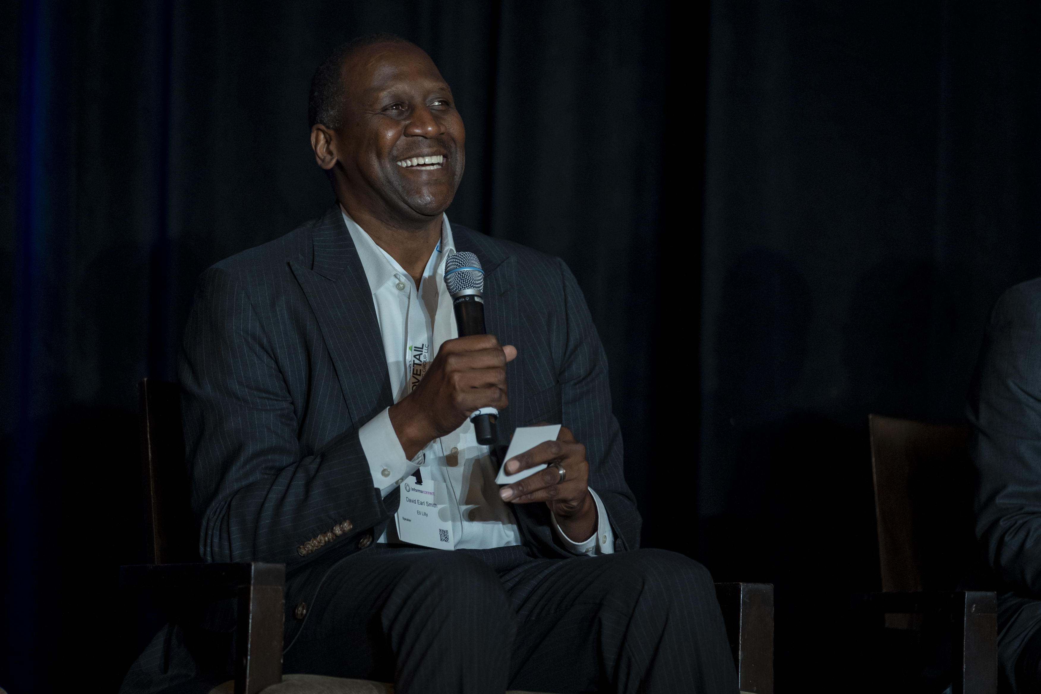 A speaker smiles as he holds a microphone.