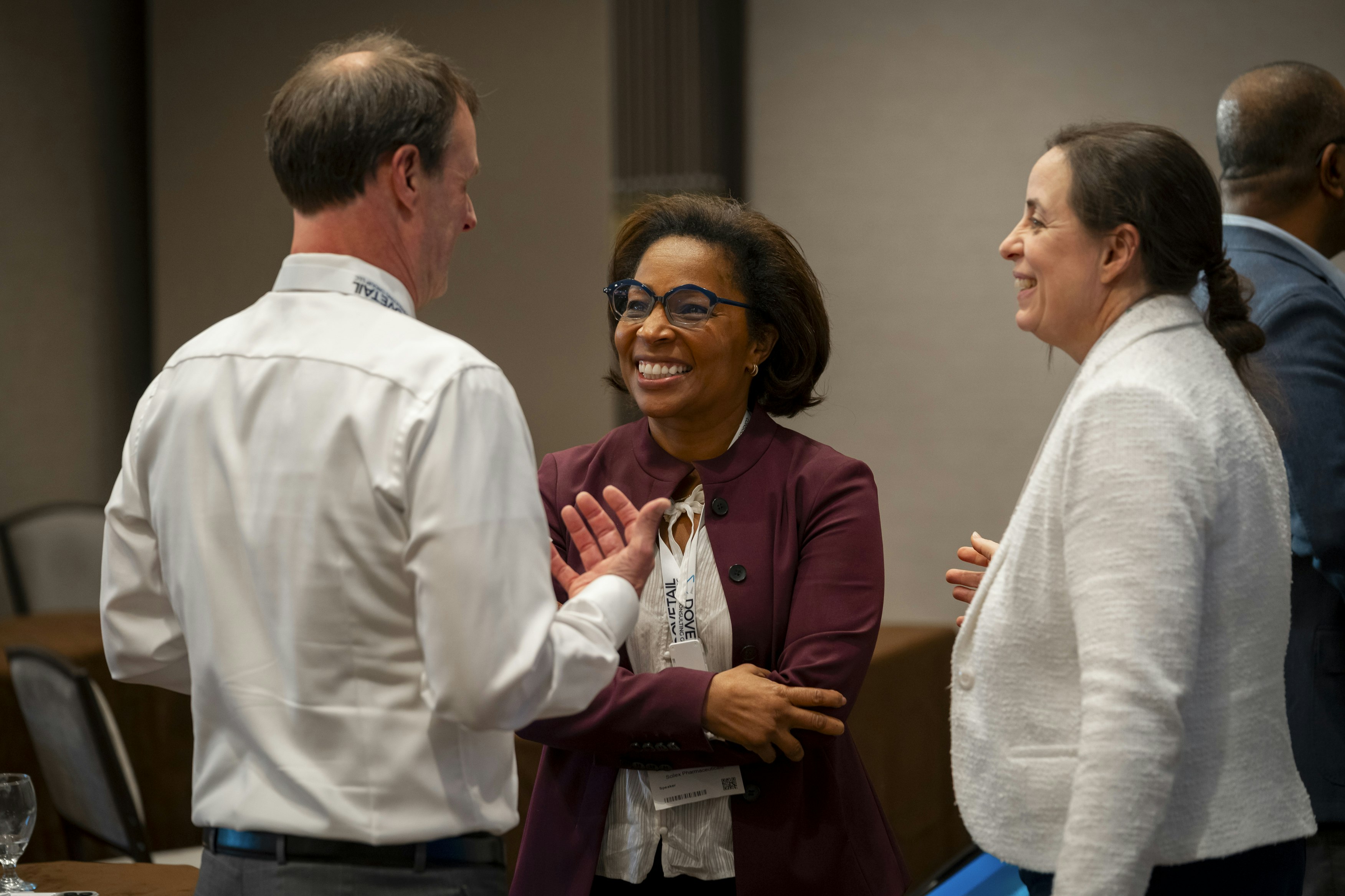 Three attendees are engaged in conversation, they are smiling.