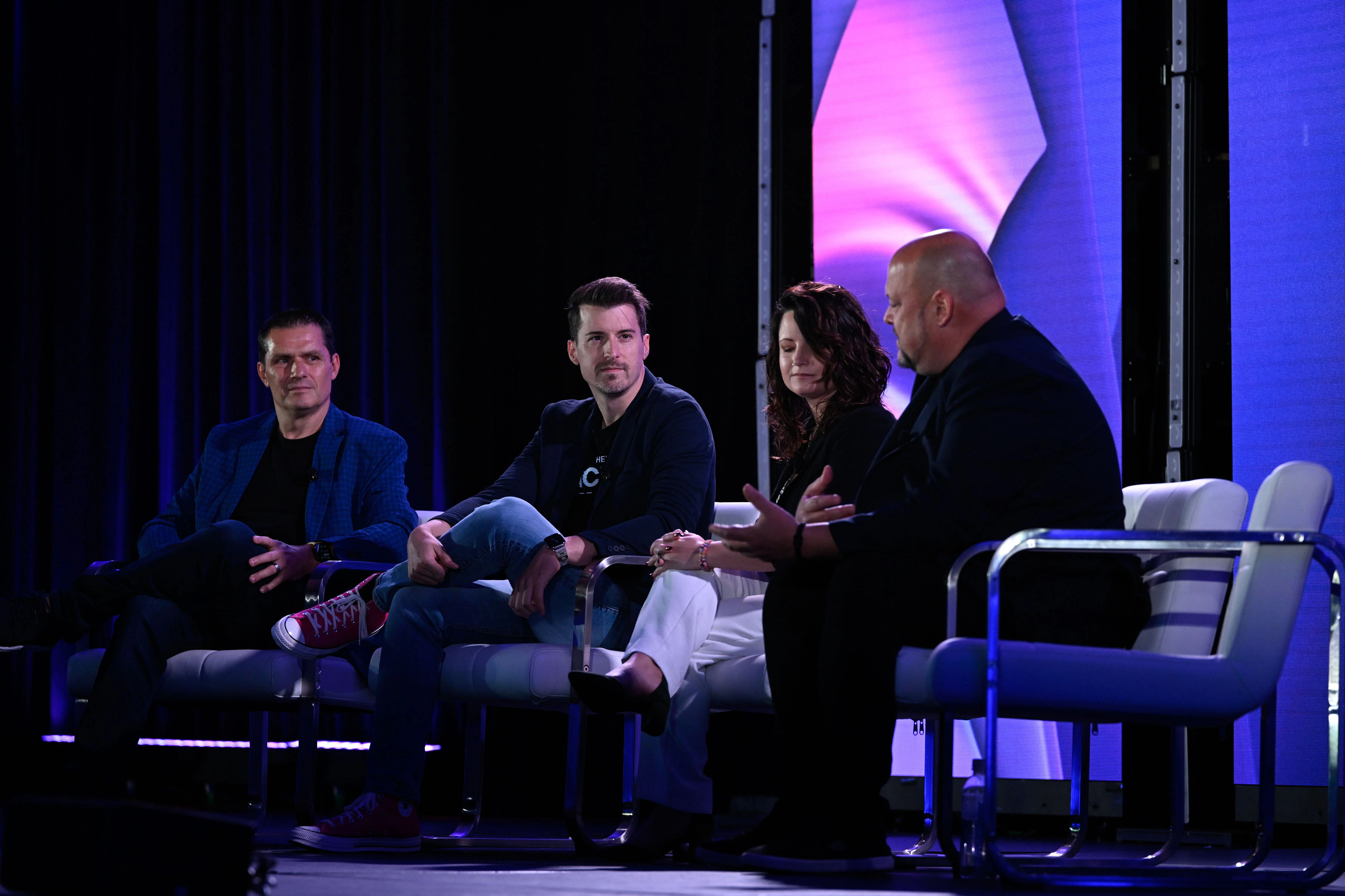 A photo of three men and a woman sitting onstage participating in a panel discussion.