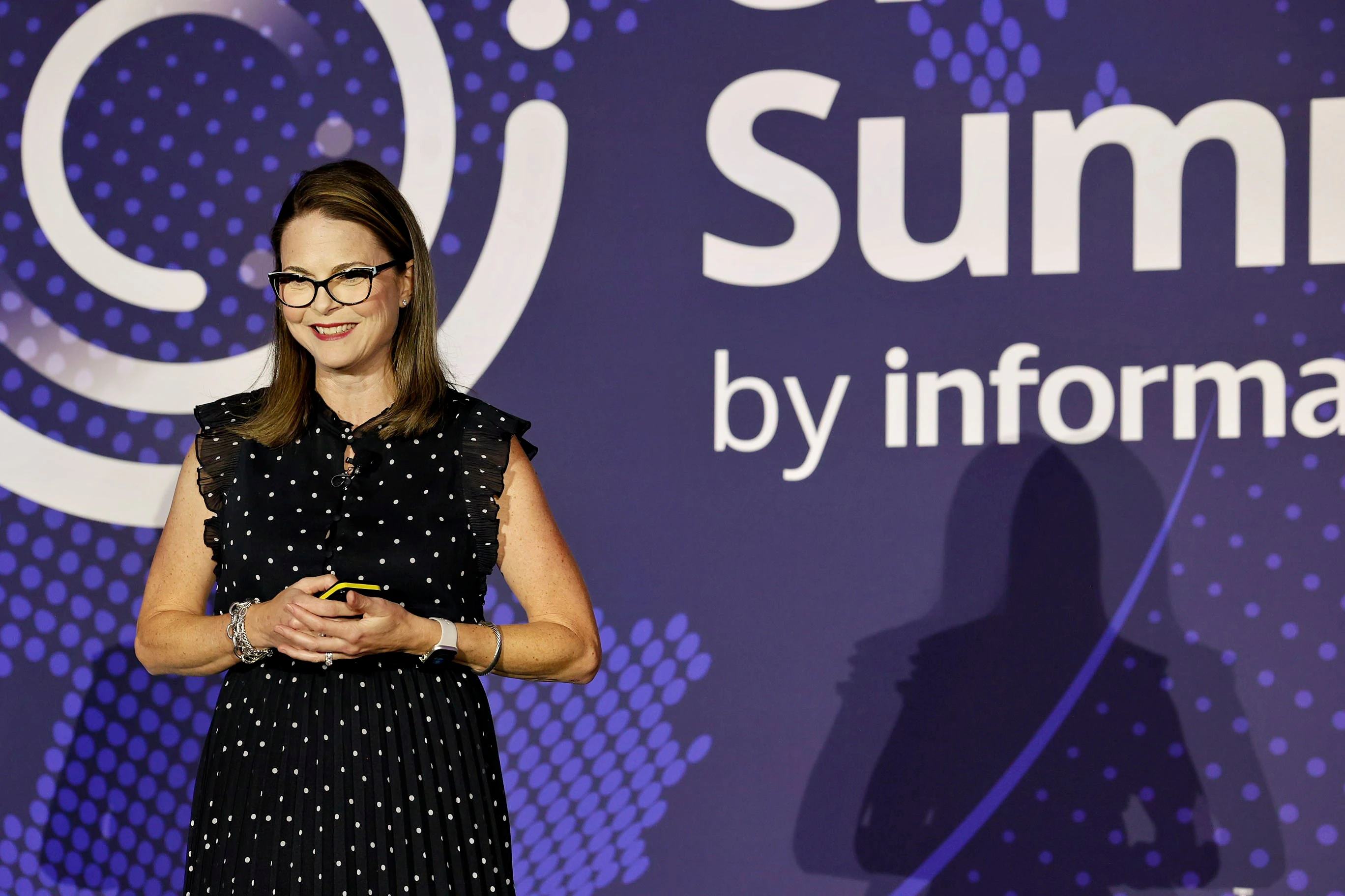 Two women and one man on stage smiling and holding their awards.