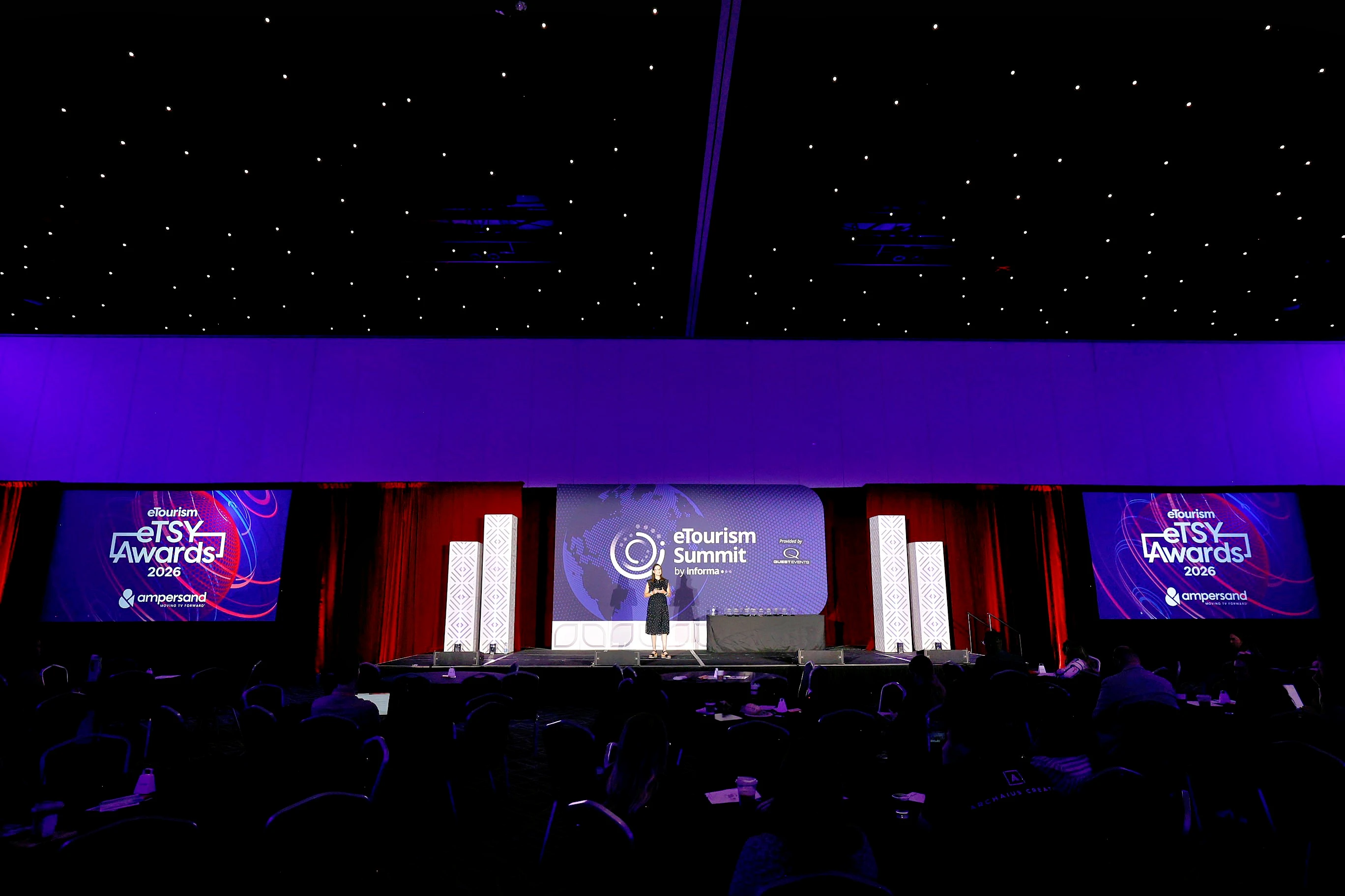 A woman with red hair in a black dress shaking hands and accepting an award from a man in a black suit.