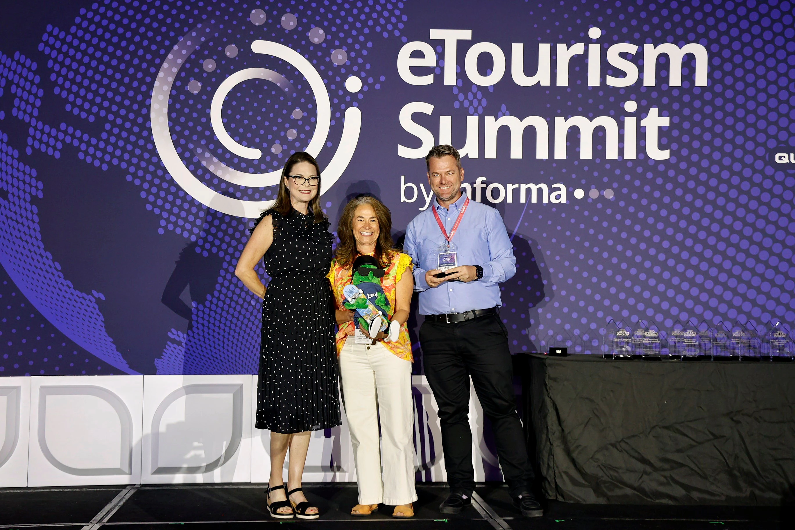 A group of professionals on stage at eTourism Summit smiling and holding their eTSY Awards.