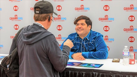 Harvey Guillen is talking to a fan at his table