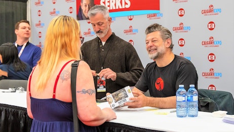 Andy Serkis smiles at a fan at his table