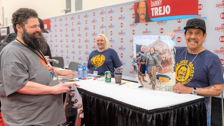 Danny Trejo holds up a signed poster at his table