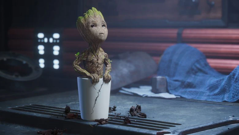 Baby Groot is in a white pot looking up at the ceiling.