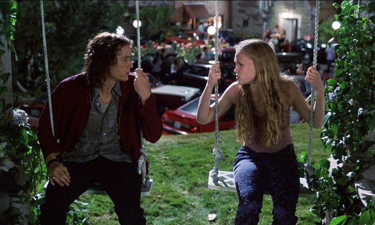 Patrick Verona (Heath Ledger) and Kat Stratford (Julia Stiles) sitting on a pair of swings.