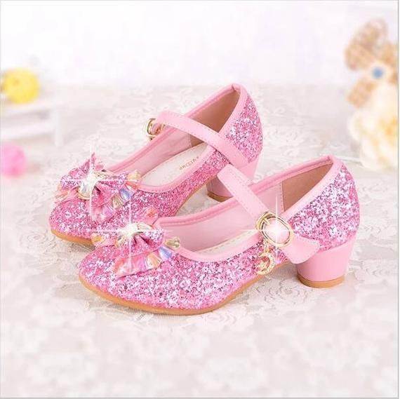 Two sparkly pink children's sized slippers with pink bows on them.