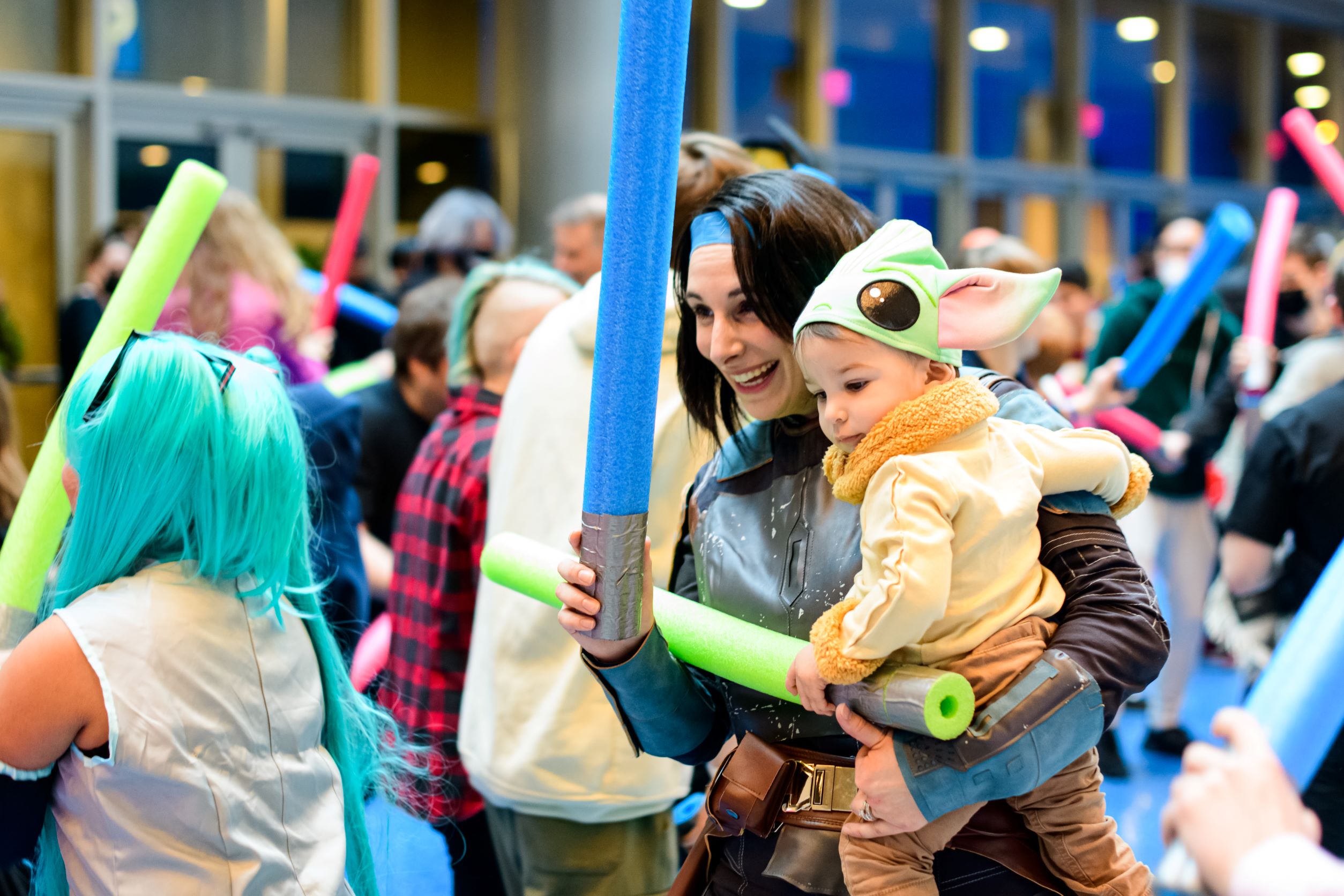 Mom and child dressed as Bo Katan and Grogu enjoying the lightsaber battle