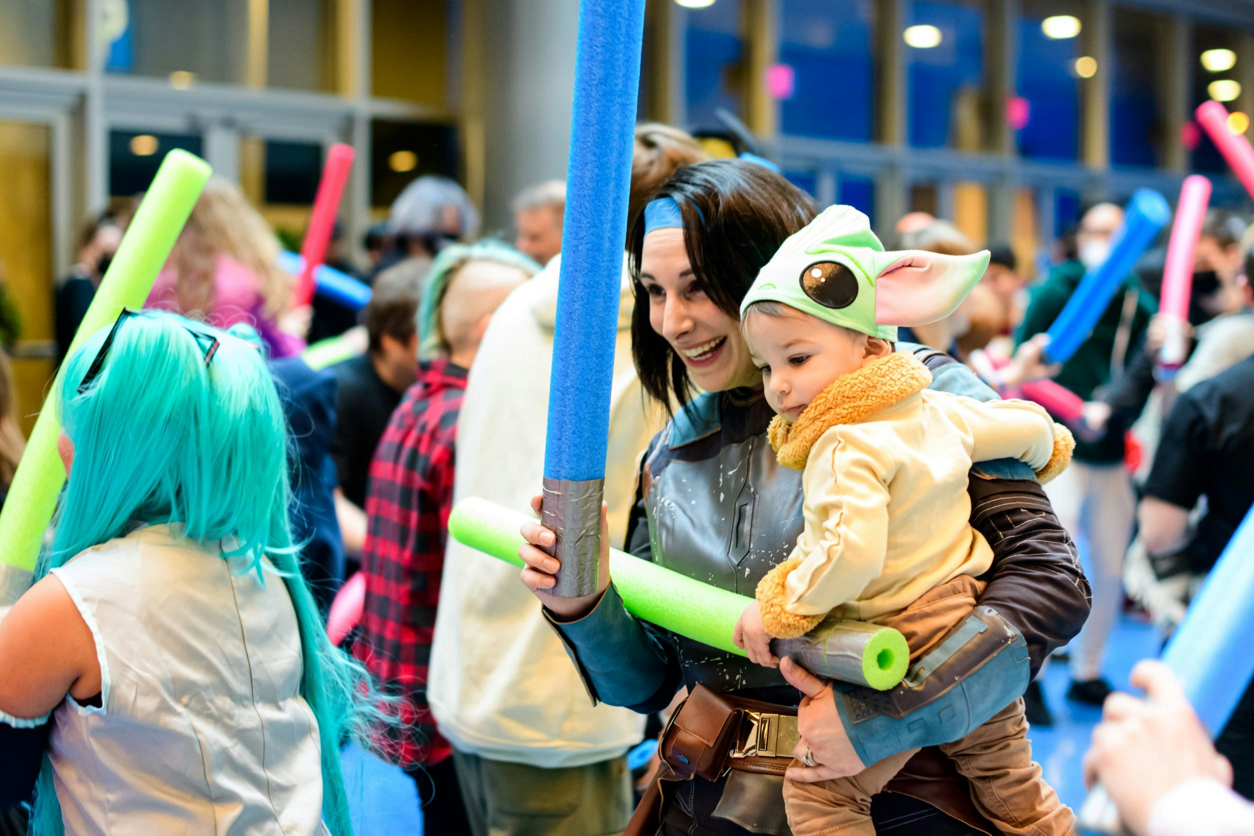 Mom and child dressed as Bo Katan and Grogu enjoying the lightsaber battle