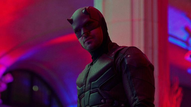 Matt Murdock in his Daredevil outfit looking serious in a room lit with blue & red LED's