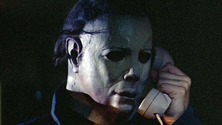 Michael Myers, the main antagonist of the Halloween series, calling someone on a telephone.