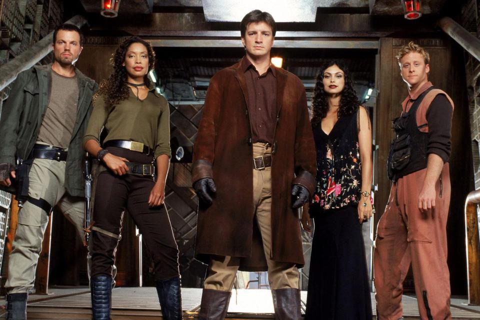 A photo of member of several cast members of Firefly, all dressed up in their character's outfits. From left to right (actor's name): Jayne Cobb (Adam Baldwin), Zoë Washburne (Gina Torres), Malcolm "Mal" Reynolds (Nathan Fillion), Inara Serra (Morena Baccarin), & Hoban Washburne (Alan Tudyk).