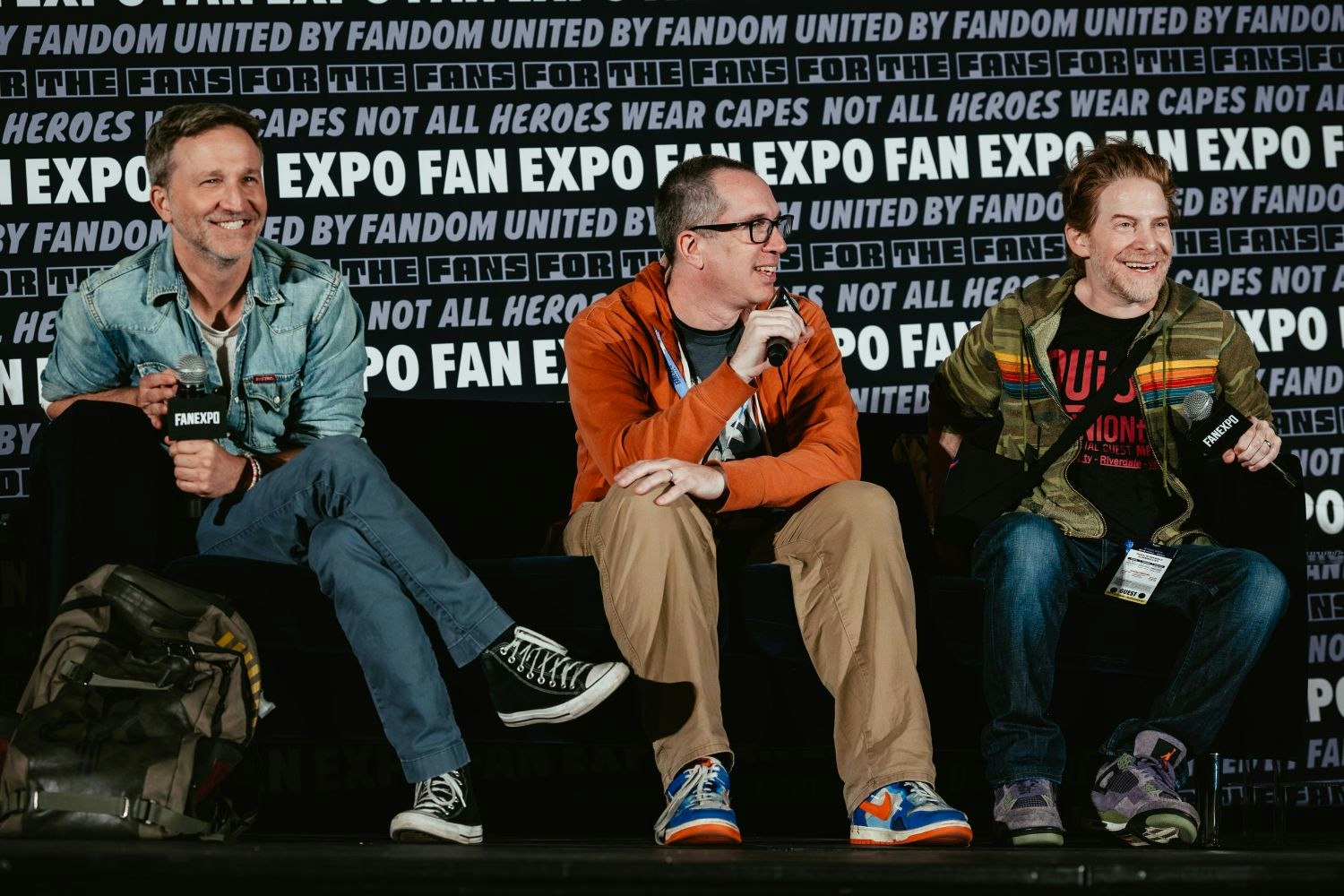 Three creators from Robot Chicken—Left to Right: Breckin Meyer, Matt Senreich, and Seth Green—sit on stage smiling and holding FAN EXPO mics during a lively Q&A session.