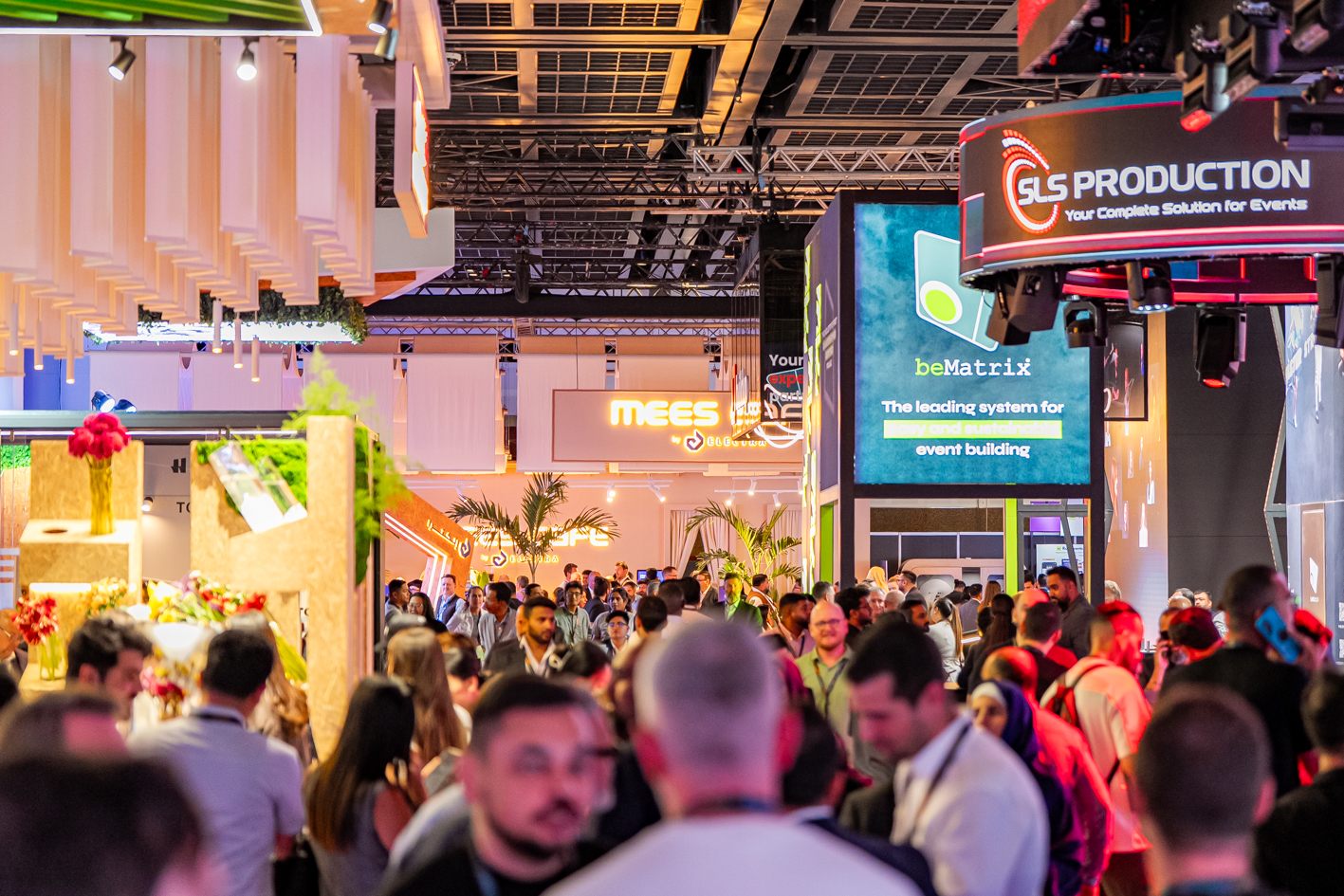 Wide view of the MEES 2025 exhibition floor at DWTC, showcasing big crowd, interactive booths, LED displays, and event tech suppliers