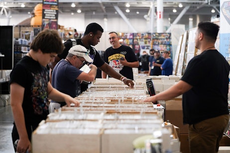 a group of fans look at comics in their boxes