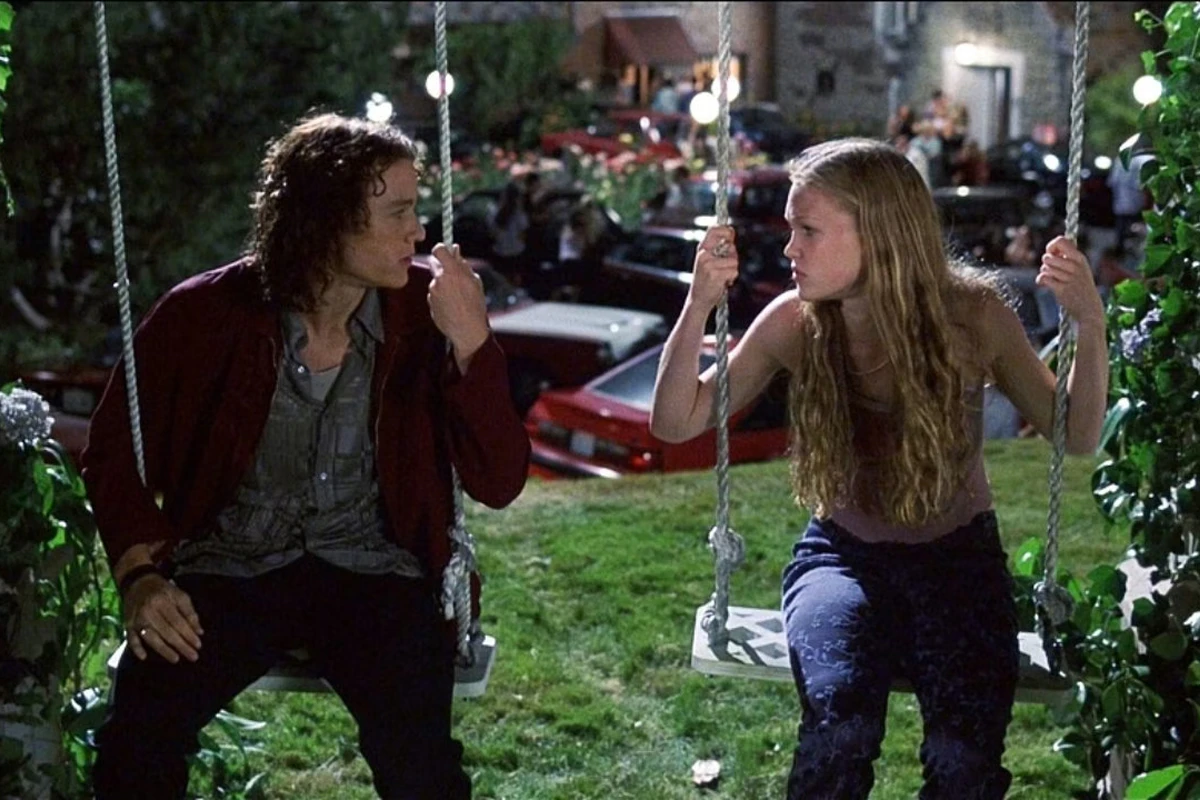 The two main characters from '10 Things I Hate About You' look at each other while sitting on swings