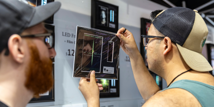 A fan shops framed film strips. Holding up a negative from Alien and inspecting the item.