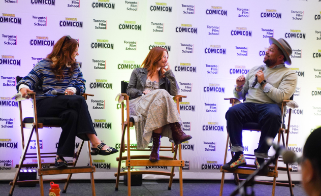 Colby Minifie (left), Valorie Curry (Centre), and Victor Dandrige (right) are seated in director's chairs on a stage. Colby and Valorie smile at Victor as he addresses them both. 
