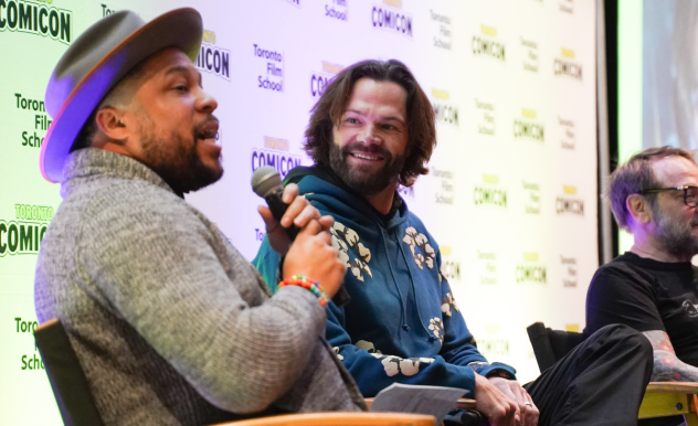 As moderator Victor Dandrige speaks to the audience, Jared Padalecki looks on, listening and smiling.
