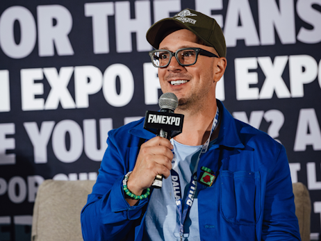 Steve Burns sitting on stage, smiling, holding a microphone.