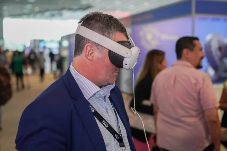 Attendee speaking with others in the event exhibition area.