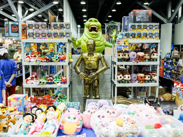 Vendor booth with C-3PO standee in the middle with plushies and Funko! Pops
