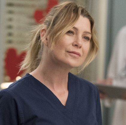 Meredith Grey from Grey's Anatomy in her scrubs smiling at a character not seen in the photo