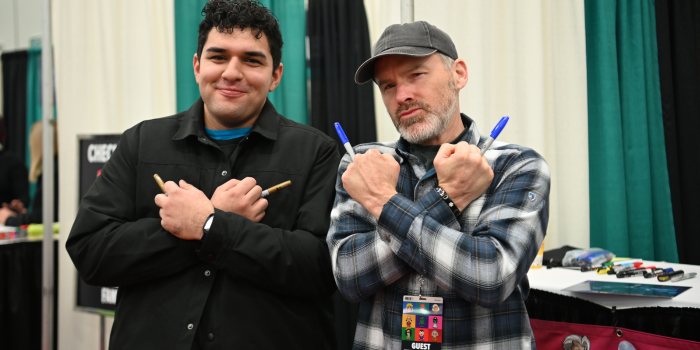 ROGER CRAIG SMITH POSES WITH A FAN. THEY DO THE WOLVERINE POSE, USING SHARPIES AS THE CLAWS.