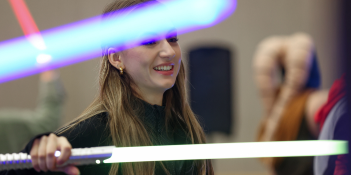 FAN BECOMES ONE WITH THE FORCE. DURING OUR SABER TRAINING WORKSHOPS, SHE WIELDS A GREEN SABER, WHILE BEING ILLUMINATED BY A FRIEND'S BLUE SABER.