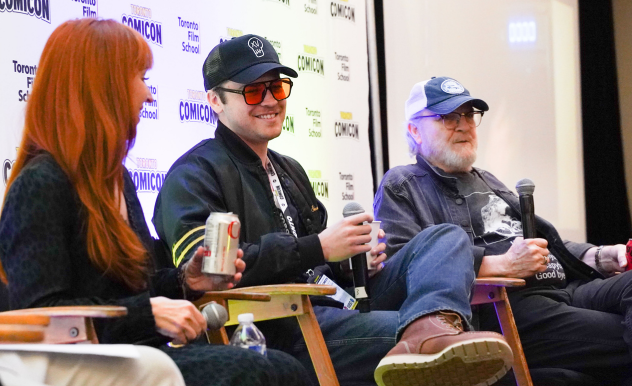 Supernatural trio are seated in a row on stage. From L-R: Ruth Connell, Alexander Calvert, Jim Beaver. All three smile as they get situated.