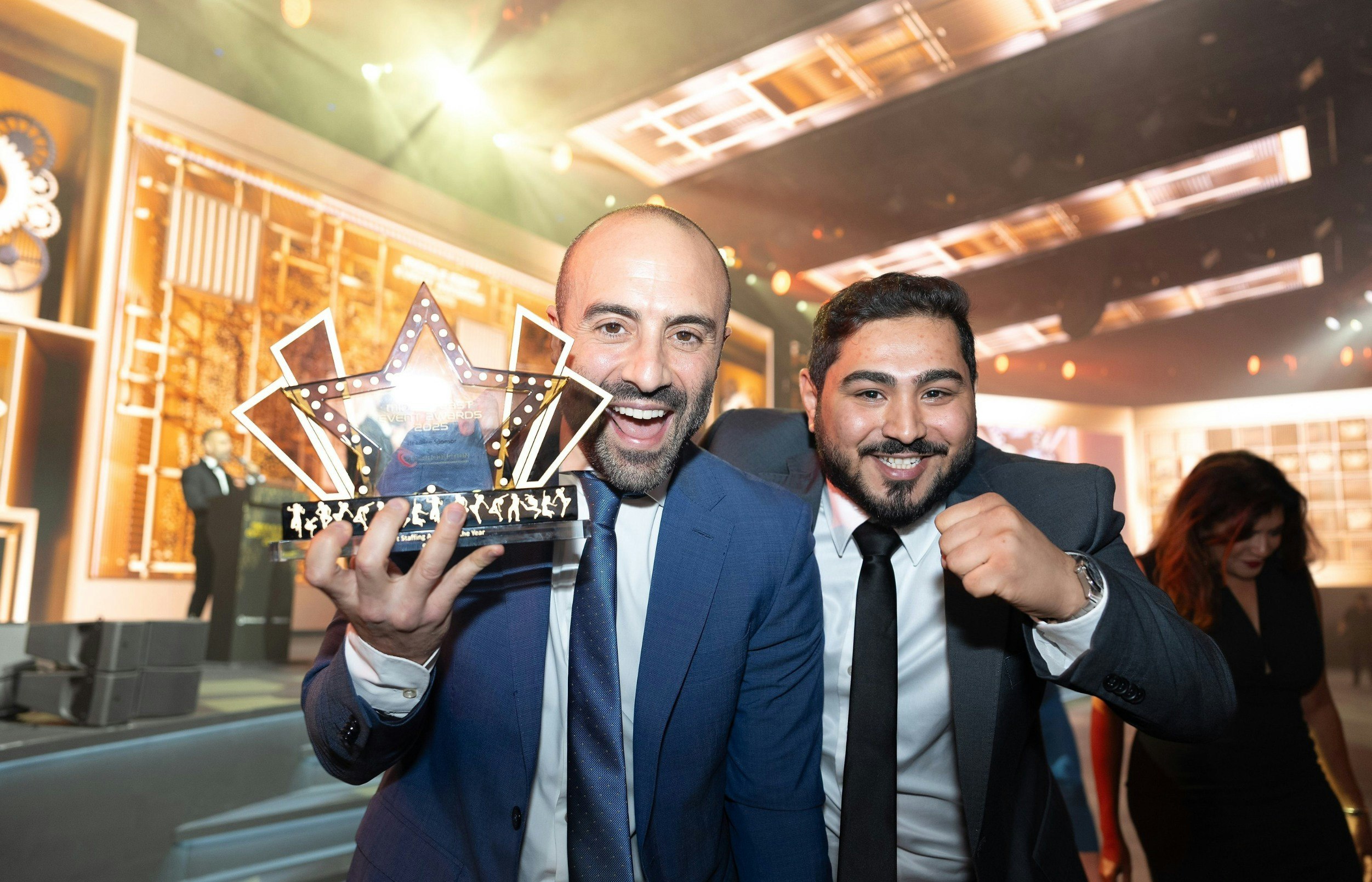 Middle East Event Awards winners celebrating on stage, holding the official Middle East Event Awards trophy at a prestigious regional events industry ceremony.