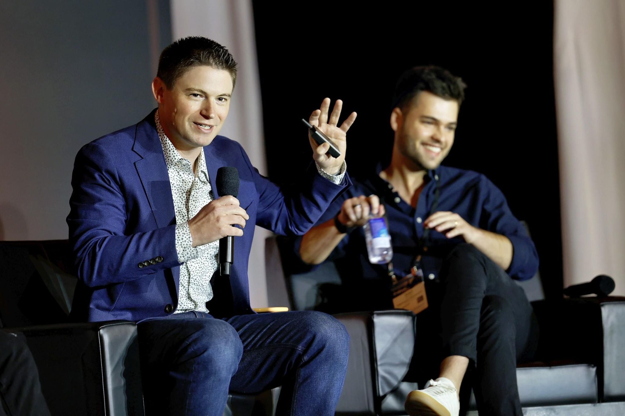 Two men with dark hair on stage addressing the crowd.