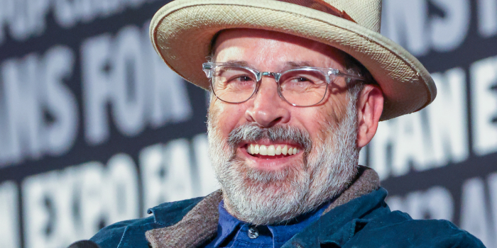 Jason Lee, dressed in all denim with a tan fedora, smiles for the camera during his panel.
