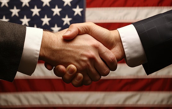 Government support. Handshake in front of an American flag symbolizing agreement and partnership