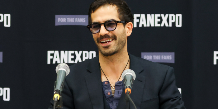 Ryan Colt Levy, with two microphones in front of him, smiles as he answers fan questions during his panel.