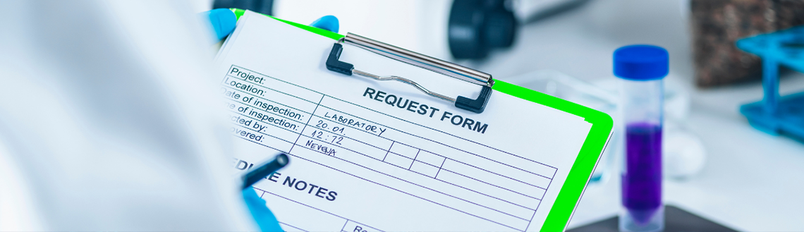 A person in a lab coat holds a clipboard displaying a list of test results in a laboratory setting.