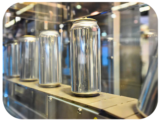 A row of metal cans moving along a conveyor belt in a factory setting