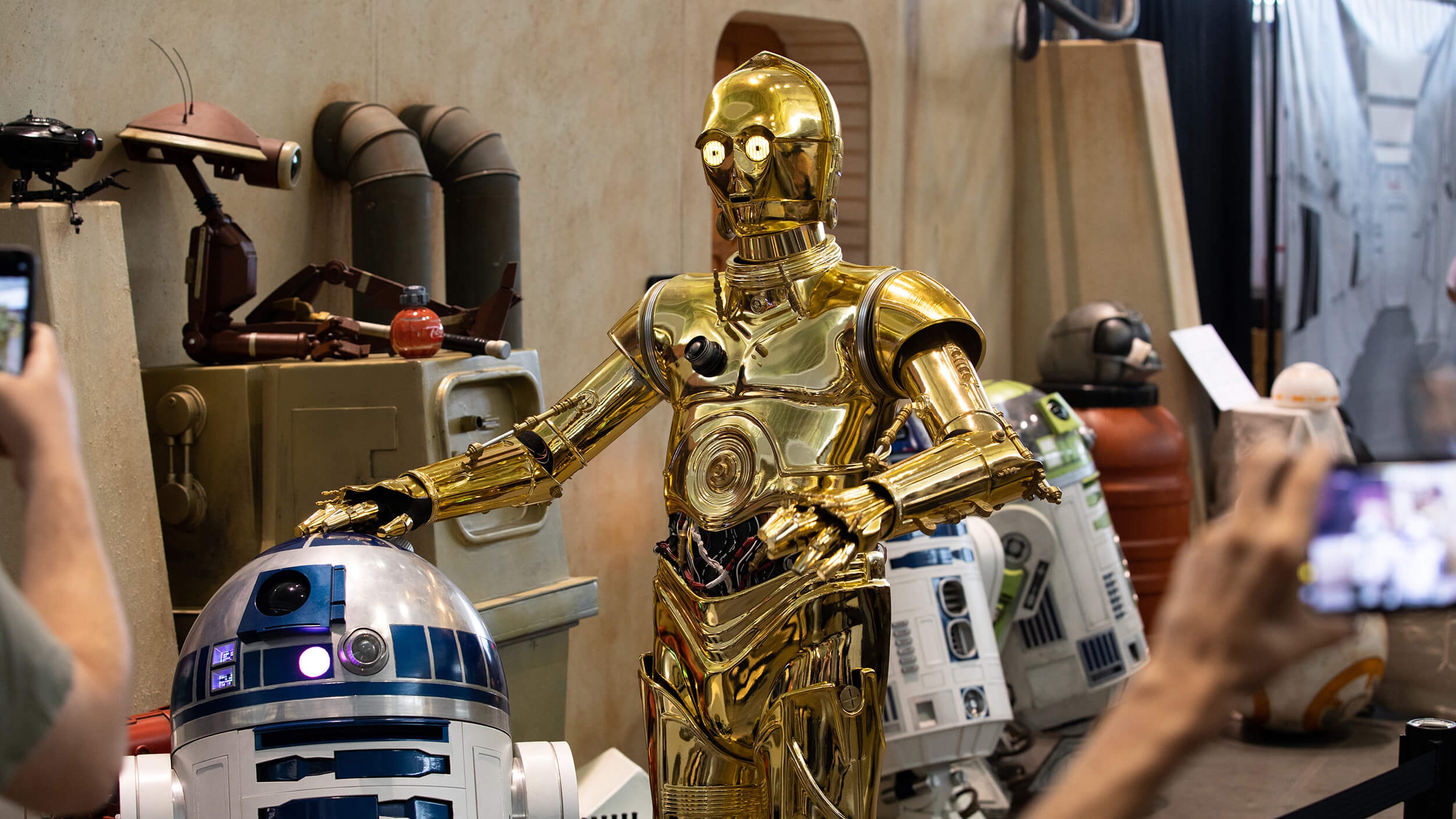 C-3PO and R2-D2 poses as fans take photos of them