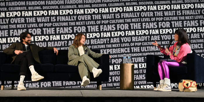 Eman Esfandi (far left) and Diana Lee Inosanto smile on as the moderator, dressed in varying shades of pink, asks questions during their main stage panel. The moderator's purse is a large chicken, pictured far right.