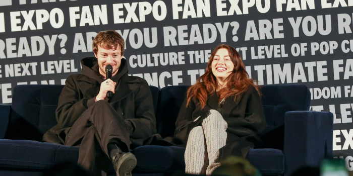 JOSEPH QUINN AND GRACE VAN DIEN, SEATED ON THE BLUE COUCH OF THE MAIN STAGE, LAUGH AS THEY ANSWER A FAN QUESTION DURING THEIR Q AND A