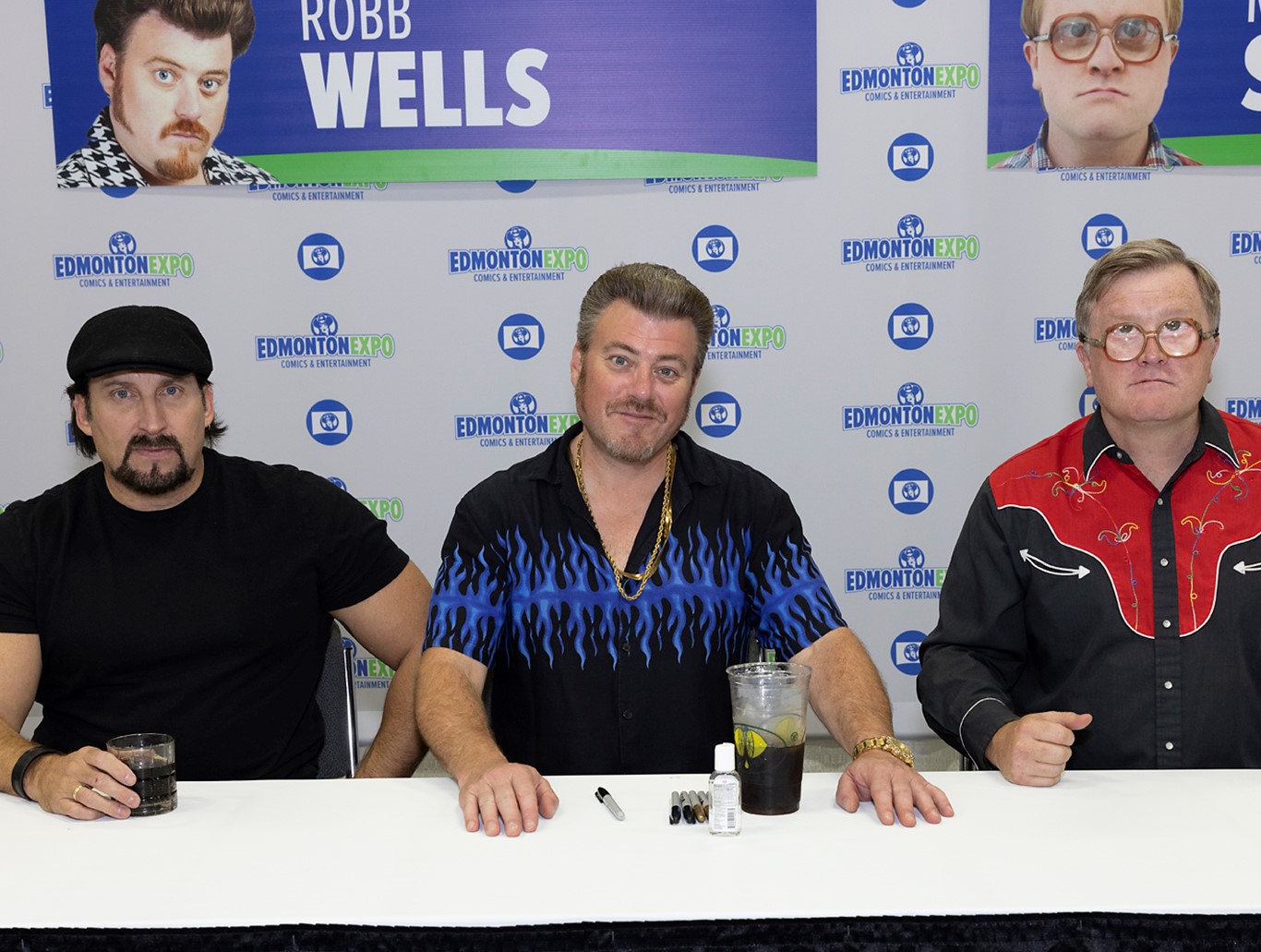 3 Trailer Park Boys sitting at the autograph table with drinks and Sharpies
