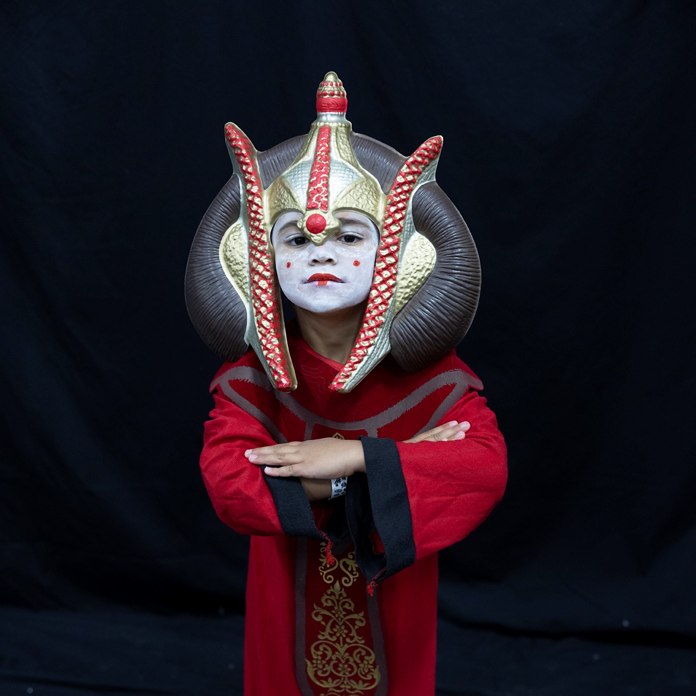 A little Padme Amidala poses on a black backdrop