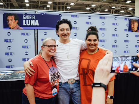 Gabriel Luna (middle) posing and smiling with two women on his left and right.