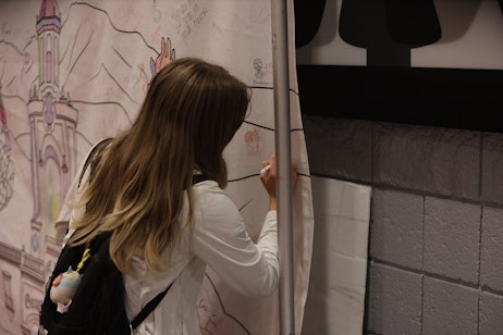 a young fan adds color to the What's Your Fandom poster, a poster of all classic Denver landmarks for the fans to add their favorite fandoms to and color in.