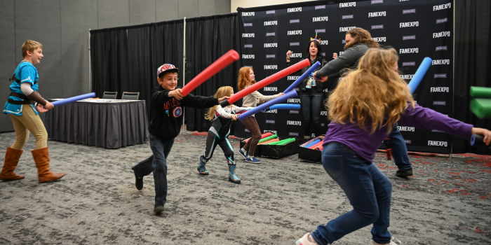 Kids running with pool noodles for light saber battle event