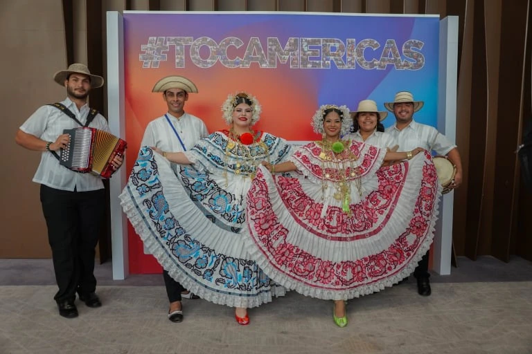 Performers in traditional attire posing at a TOC Americas display.