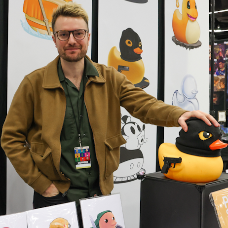 Vendor poses with giant rubber duck wearing a black mask