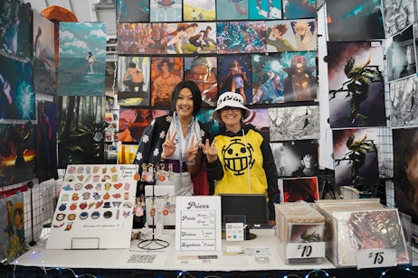 vendors posing for a photo infront of their art